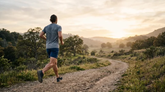 Coureur vu de dos en pleine foulée sur un chemin lumineux, symbolisant une circulation sanguine dynamique qui nourrit les muscles